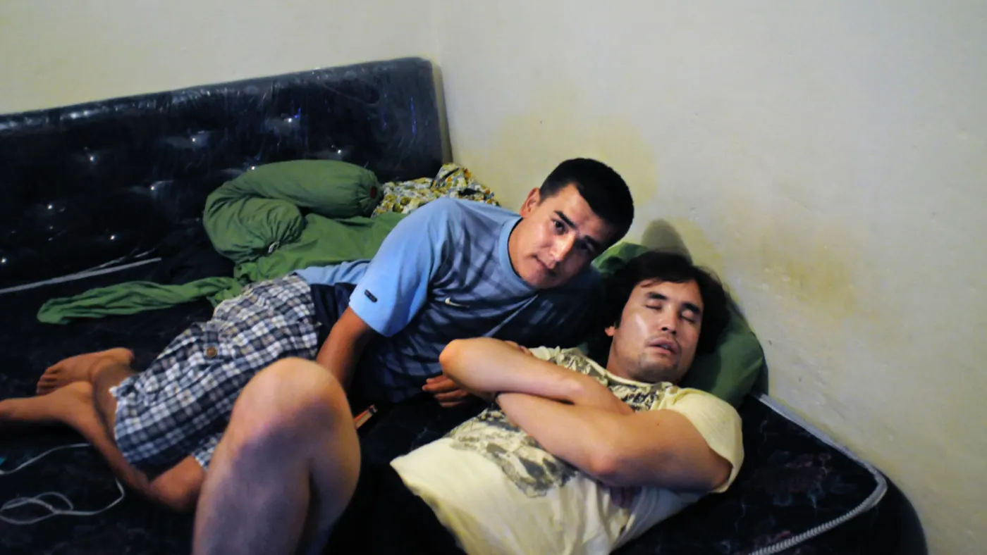Two young men on a mattress in the villa at Bogor, one awake and one asleep, 2012.